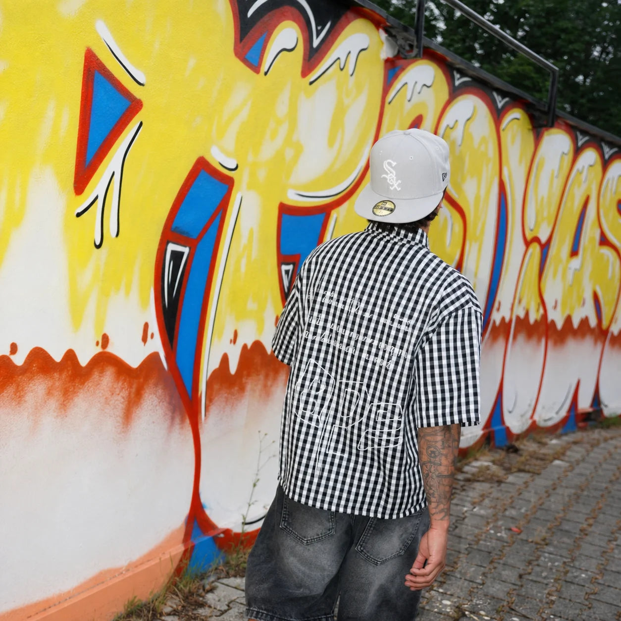 Culture23 Instagram camicia check davanti a graffiti